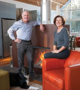 Architects Peter Ortved and Maureen O’Shaughnessy with dog Marley in front of the two-sided fireplace in their sitting area. The fireplace, from Belgium, has a pre-rusted finish of cortex steel.