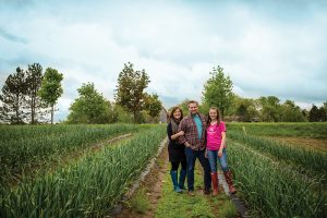 Kimberly and Tim Schneider and daughter Teaghen among the garlic crop at Dunridge Farms.