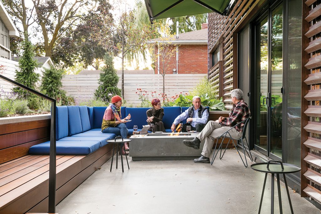 the Pirks entertain friends on the back patio under an automated retractable awning. The concrete fire table is by Chantico.