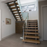 The staircase, made by Georgian Stair Co. with railings by Dennis Risk of MCR Industries, leads from the ground floor entrance up two flights to the top floor. A door to the garage (not seen) is on the left.