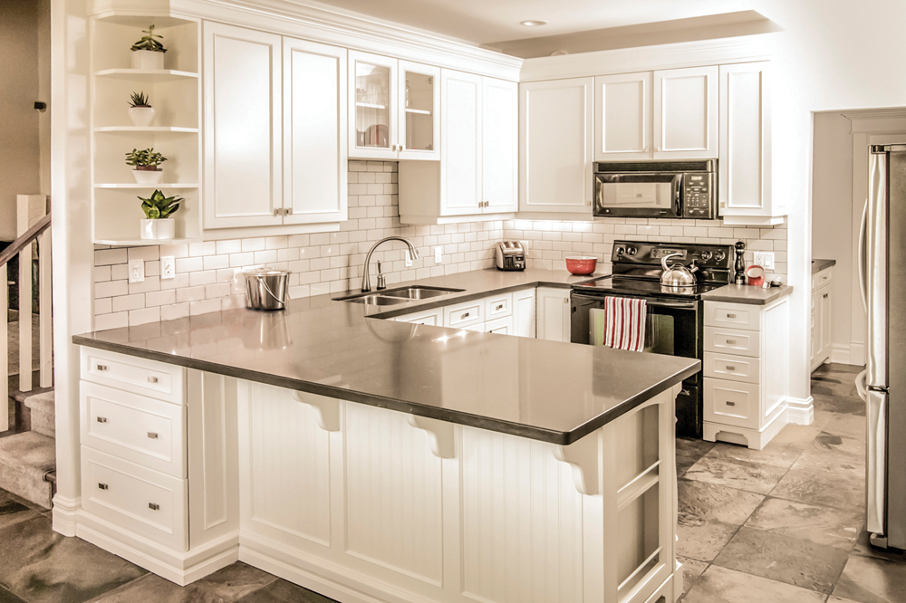 Kitchen Painters transformed this dated kitchen’s wood cabinets with some paint and new hardware, and updated the countertop and fixtures to give it a whole new look.