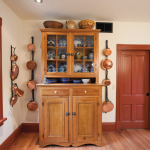 The refinished pine hutch in the kitchen, surrounded by Jill Bates’ collection of copper pots.