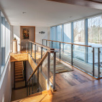 Glass panels in the stairway keep the bridge open and bright. At the far end is the entrance to the master suite.