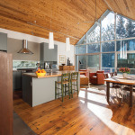 Sliding doors at the back of the house open to a cedar deck overlooking the woods. In the kitchen a long rectangular slit of window provides an unconventional backsplash. Engineered hemlock flooring contains radiant heat and adds visual warmth to the minimalist space.