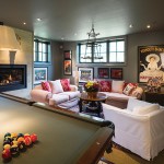 Large windows shed plenty of light on the high-ceilinged basement recreation room, while the “disco” area is enlivened by framed photographs and vintage album covers.