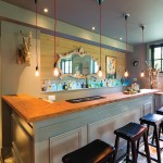 An impressive collection of tequila bottles line up behind the wet bar. Red string lights add a whimsical touch.