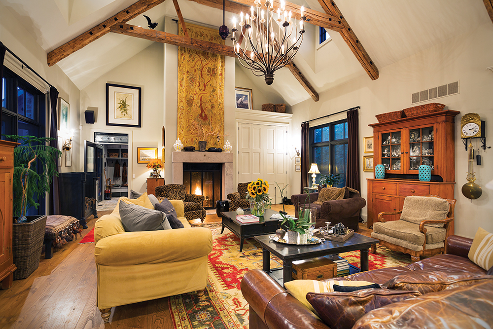 A limestone wood-burning fireplace with a walk-in hearth is the focal point of the high-ceilinged great room. The furnishings are an endearing and enduing mix of family heirlooms and thrift-store finds.