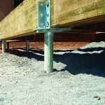 Helical piles are manufactured steel foundation posts that screw into the ground, and are quicker to install with less soil displacement than concrete footings.