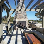 An imposing natural stone propane-fuelled fireplace anchors the living area in this outdoor kitchen and living room designed and built by Natural Stonescapes.