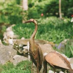 The Majors entertain their friends in their outdoor space. A tray of planted herbs from Kettlewells is set up on the granite outdoor countertop for easy access. Heron sculptures pose on the side of the rock-edged stream that runs through the Major’s garden.