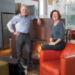 Architects Peter Ortved and Maureen O’Shaughnessy with dog Marley in front of the two-sided fireplace in their sitting area. The fireplace, from Belgium, has a pre-rusted finish of corten steel.