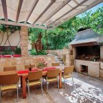 A pergola with a canvas shade covers an outdoor kitchen.