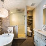 Homeowner Marie-Claude Park had the drywall removed from the walls of the main upstairs bathroom and scrubbed them for a rugged look. The crystal globe chandelier is a glittery contrast.
