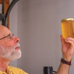 Richard Elzby admires the end result: a golden jar of liquid raw honey.
