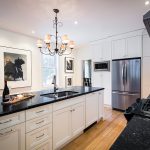 The renovated kitchen was kept simple and classic with black quartz countertops, white Shaker-style cabinetry and plenty of white walls for framed photography.
