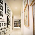White walls and floors in the upstairs hallway provide a clean backdrop for framed photographs.