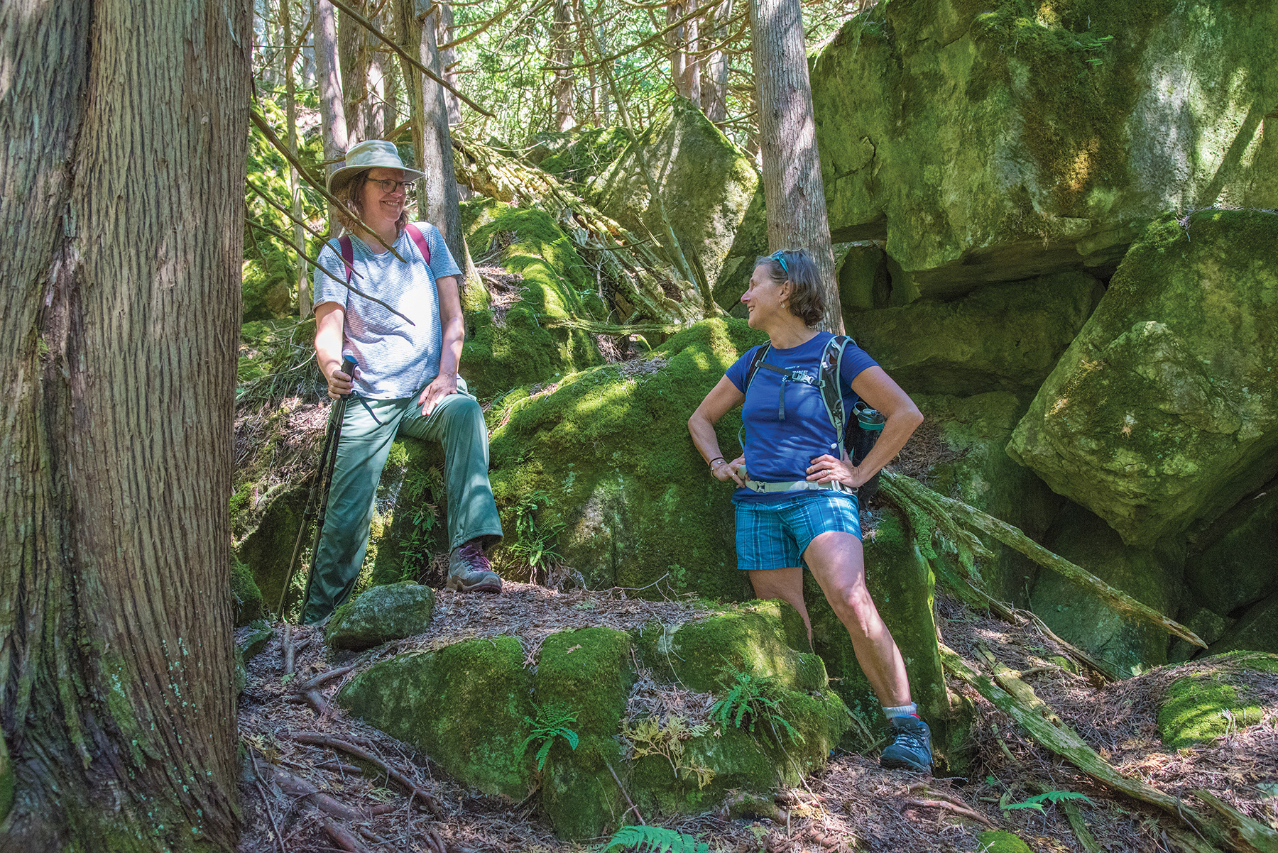 As pockets of cold air waft up from the crevices, Leslie Piercey and Shanna Reid cool off amidst the mossy rocks of a massive boulder field on the Silent Valley Trail.