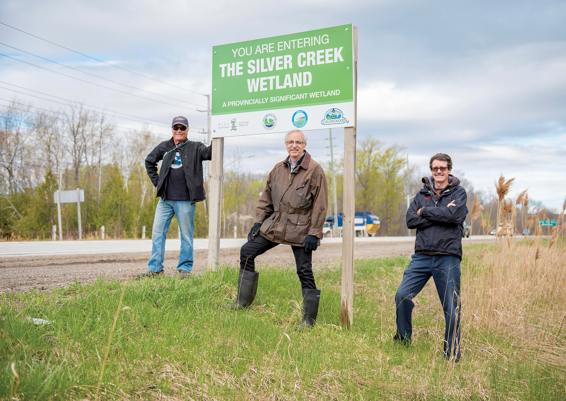 Members of the Save Silver Creek Wetlands community group (l-r) Duncan Bristow, Paul Neate and Chris Mifflin pose near a sign on Highway 26 marking the entrance to the wetland.
