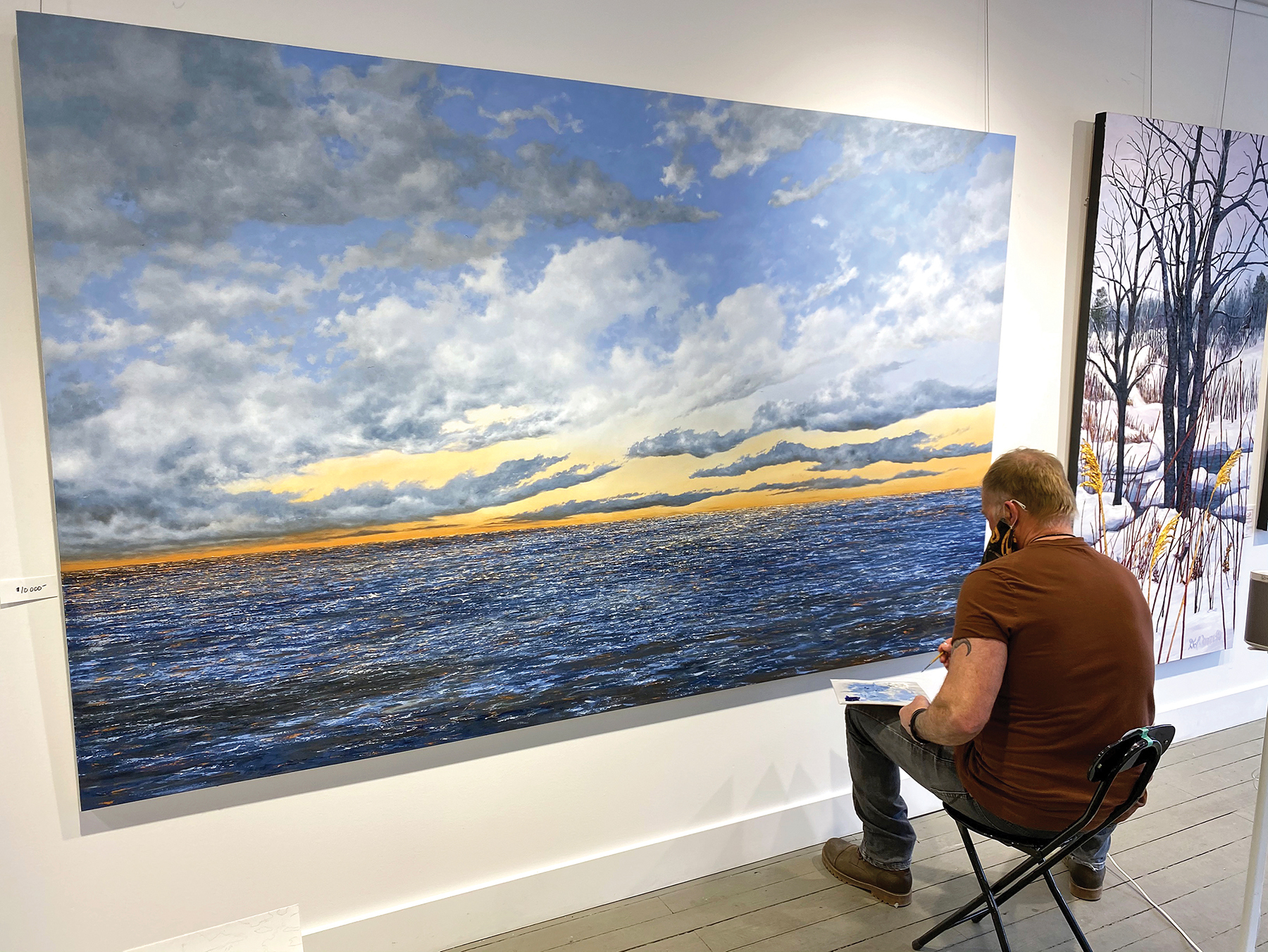 Lorne McDermott touches up his 60 x 96 seascape, “In Search of Serenity,” at the Loft Gallery in Thornbury.