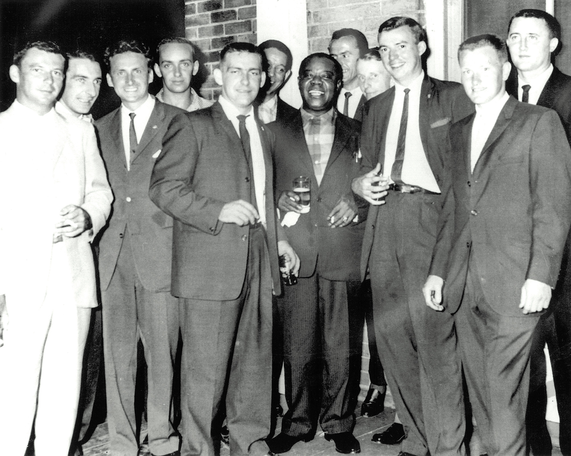 Louis Armstrong in Collingwood. Left to right: Dee Dee Bryan, T.J. Brown, unknown, Wayne Hartle, Buddy Brown, Trummy Young, Louis Armstrong, unknown, John Sheffer, Frank Bryan, Roger Lockhart, David Christie.
