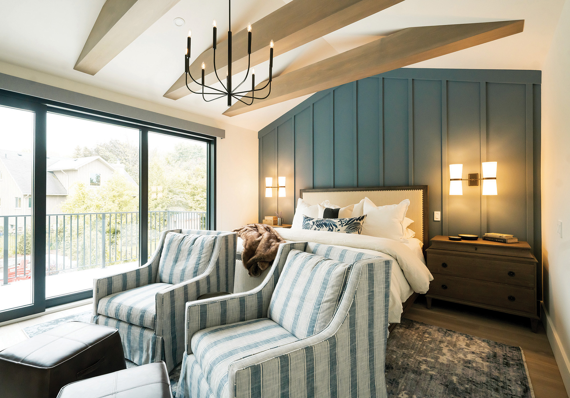 A deep blue feature wall and natural textures in the principal bedroom. Rustic chandeliers and heated floors throughout the home.