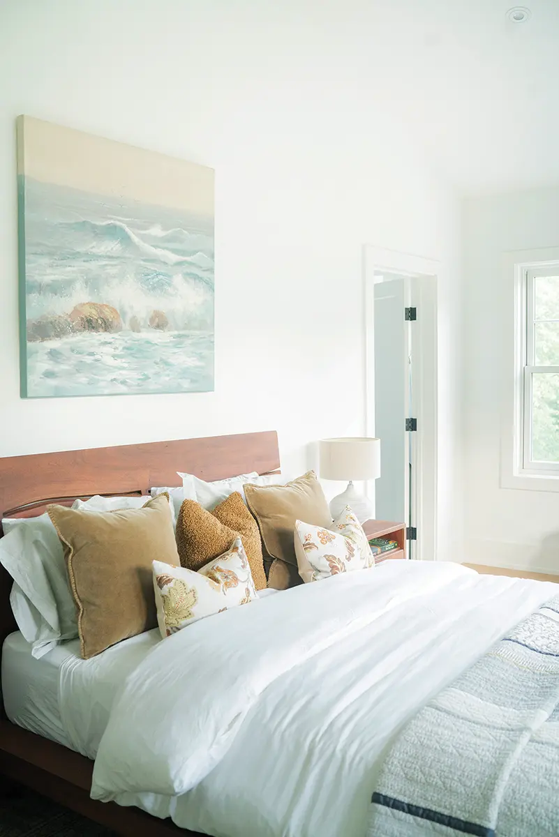 The light-filled primary bedroom and bathroom are a study in warm tones on white.