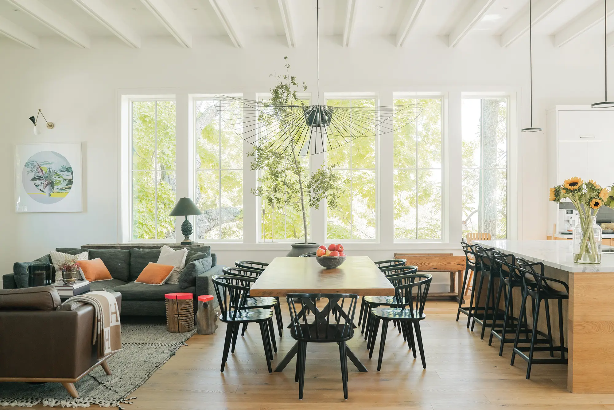 The pièce de resistance: an enormous wooden dining table with simple black wooden Windsor chairs. Floating above the table is a light fixture shaped like a wide-brimmed lady’s hat.