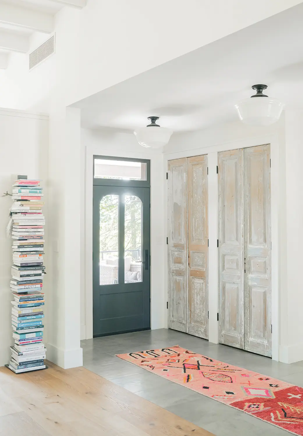 The light-filled entrance hall features antique closet doors from The Door Store. The wood-burning stove was salvaged from the schoolhouse and refinished.