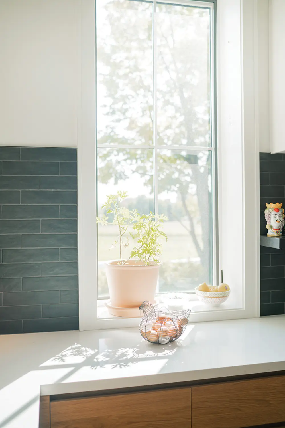 The kitchen features a white wall of cupboards and a white Caesarstone island, while the backsplash offers a dramatic contrast in black.