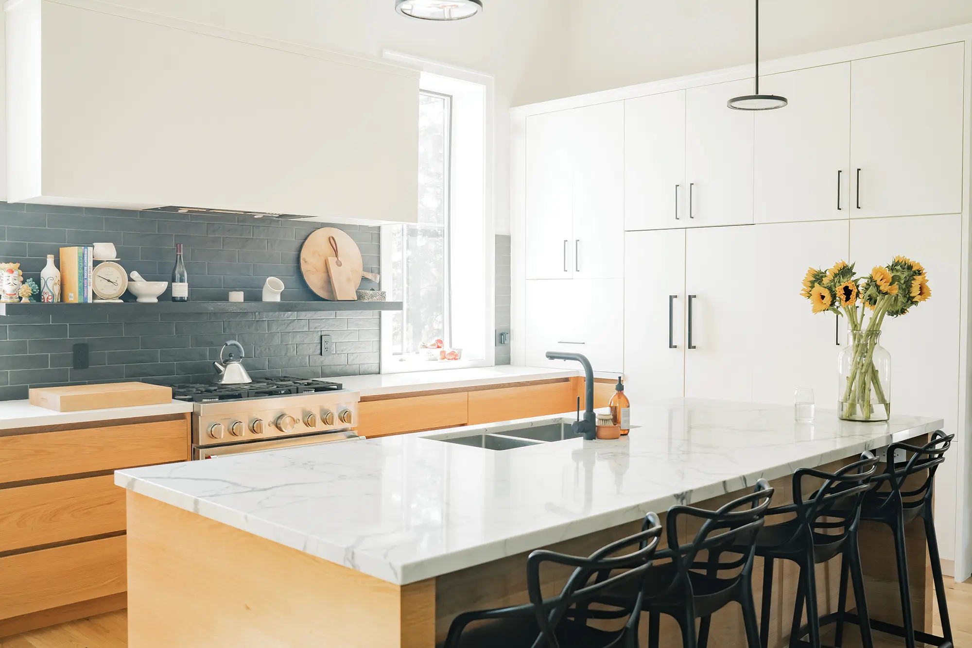 The kitchen features a white wall of cupboards and a white Caesarstone island, while the backsplash offers a dramatic contrast in black.