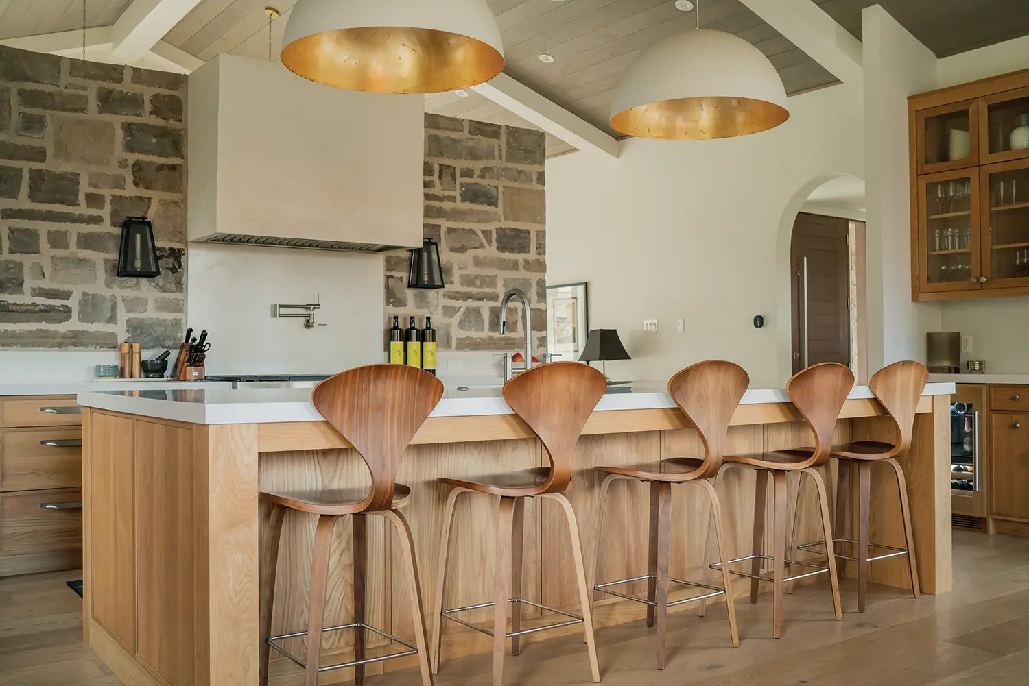 The kitchen features a white wall of cupboards and a white Caesarstone island, while the backsplash offers a dramatic contrast in black.